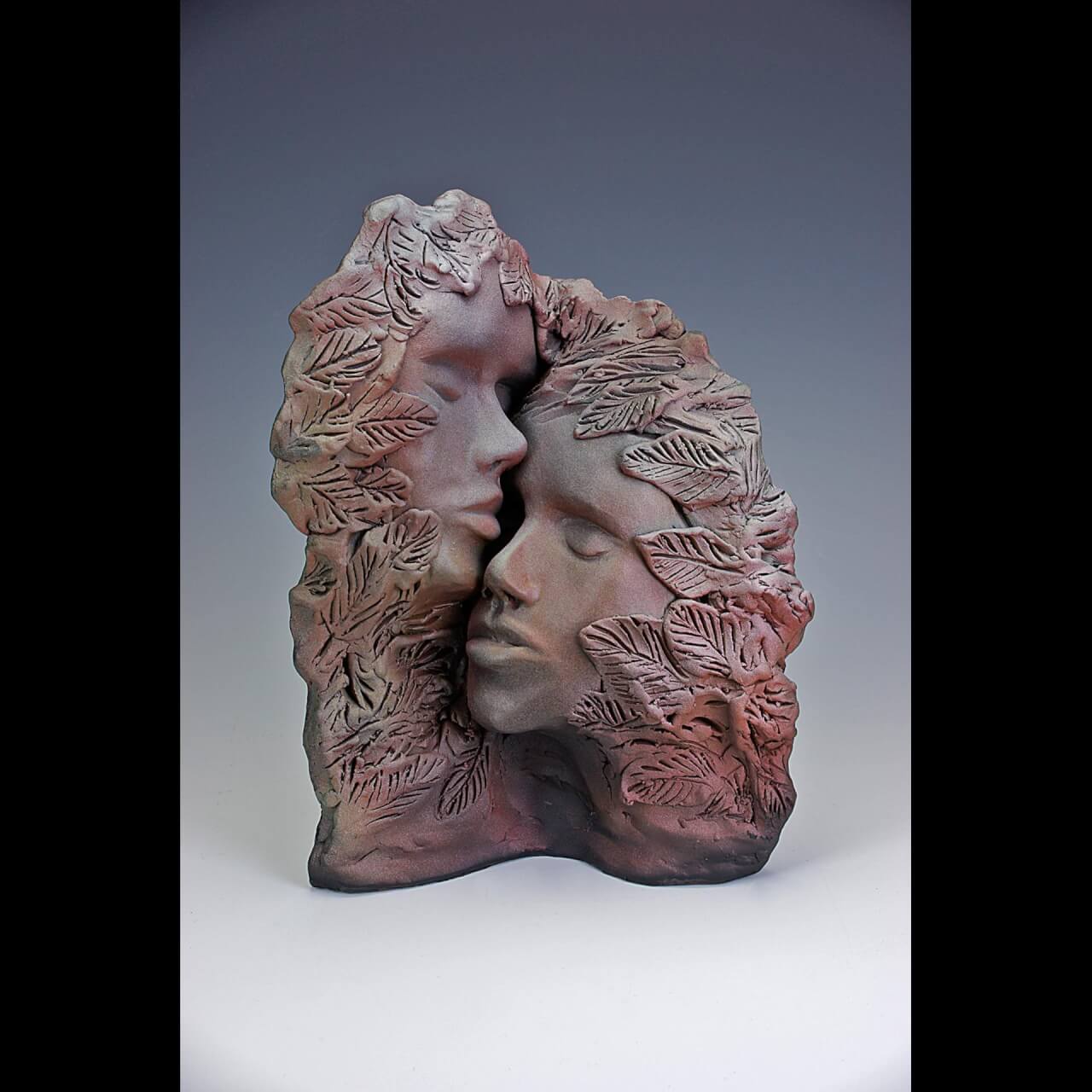 two face carved from red clay facing each other