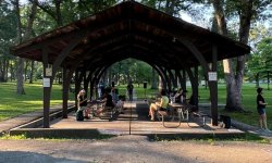 james tutson singing in an upper city park shelter with attendees sitting at picnic tables