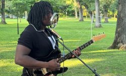 james tutson singing into his microphone and playing guitar