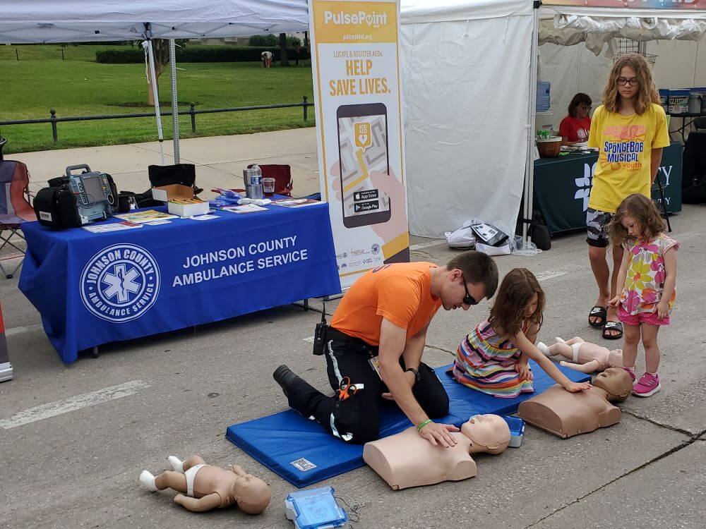 johnson-county-ambulence-staff-showing-child-how-to-do-cpr