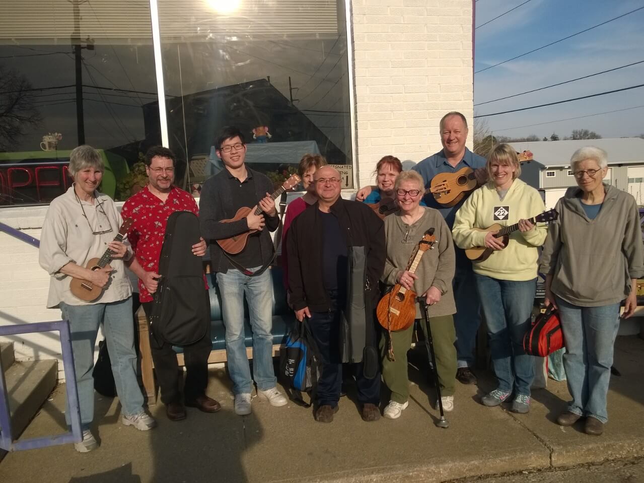 group-of-people-standing-outside-of-building-with-their-ukuleles