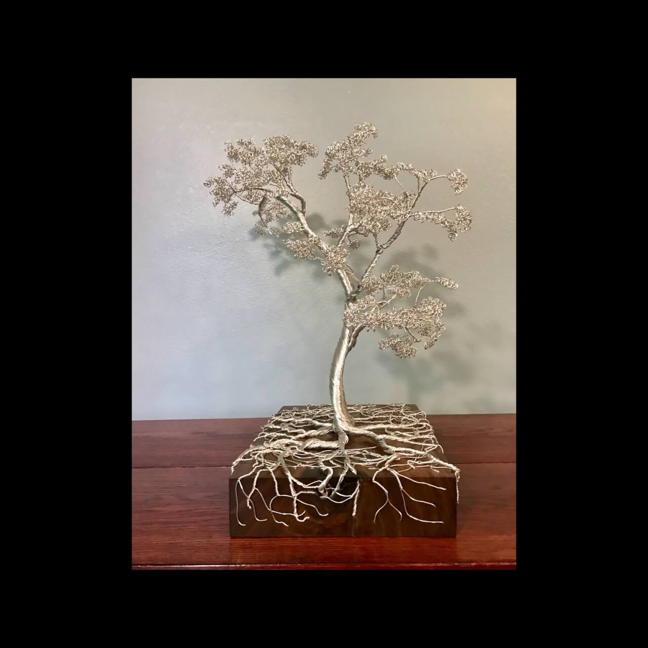 metal wire tree with roots mounted on a wooden block